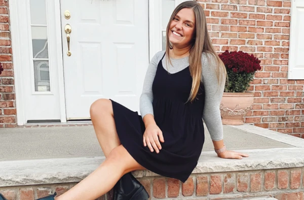 A smiling woman sitting on a porch in front of a house.